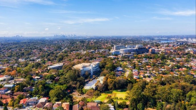 A panoramic view of a suburban neighborhood with tree-lined streets, modern buildings, and a city skyline in the background