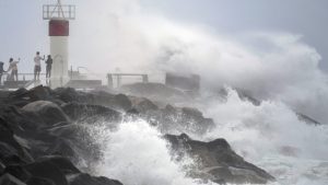 Waves crash on to rocks as people stand at the Spit, in the Seaway on the Gold Coast