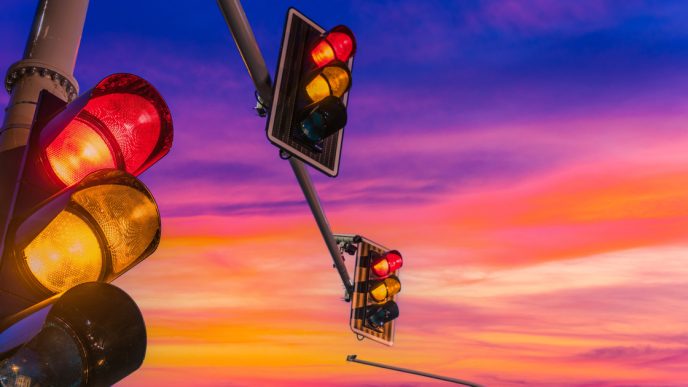 Traffic lights showing red and amber against sunset backdrop